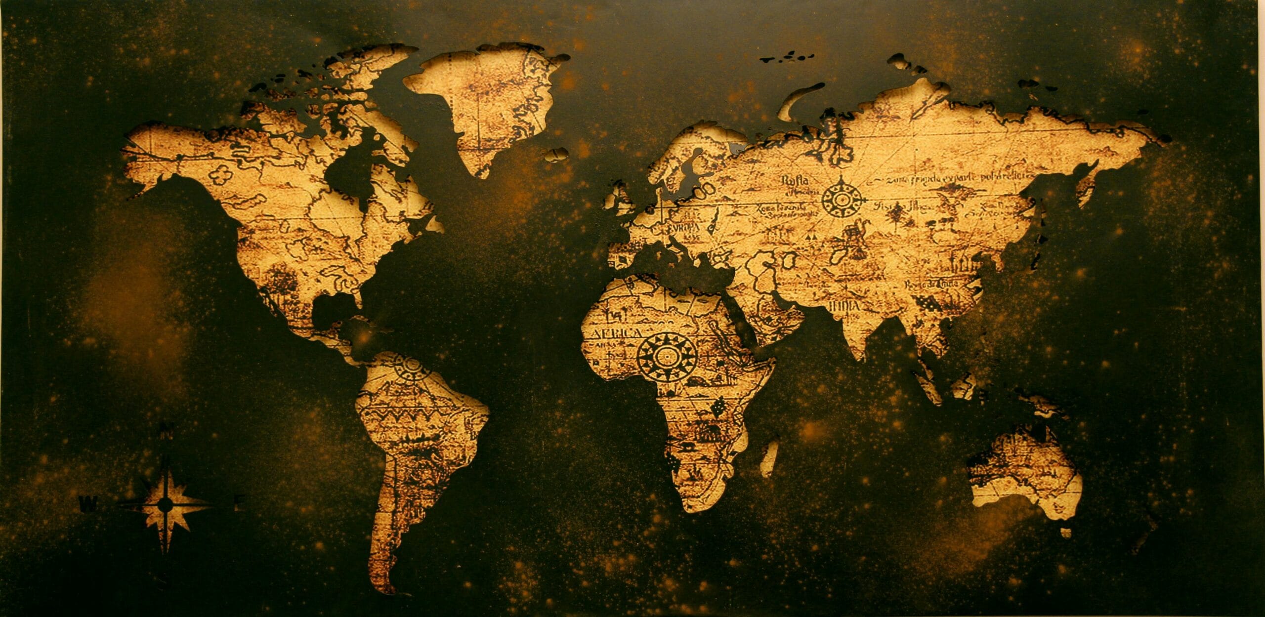 An antique-style world map with a golden-brown textured design on a dark background. The continents are outlined with intricate details, including compass roses and faded script, evoking a vintage, historical aesthetic. UK and Europe DMC