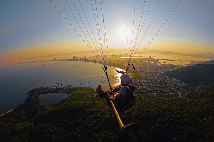 Da Nang Paragliding – Paraglider flying over Da Nang coastline with Marble Mountains below.