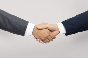Business professionals shaking hands in front of a world map, symbolizing global B2B travel partnerships.