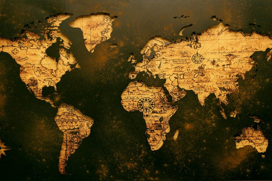 An antique-style world map with a golden-brown textured design on a dark background. The continents are outlined with intricate details, including compass roses and faded script, evoking a vintage, historical aesthetic.